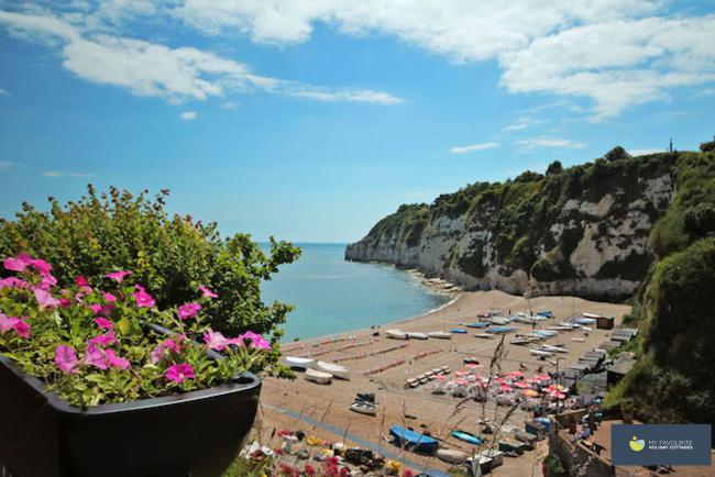 Beer Beach in East Devon Beer's shingle beach on which small fishing boats and cafe tables are laid out nestles beneath steep, vegetation-covered chalk cliffs