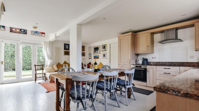 Enjoy Open Plan Living at Fall Echoes in Gresham An open plan kitchen area with dining table, fitted kitchen units, a lounge with sofas and French Windows to the garden.