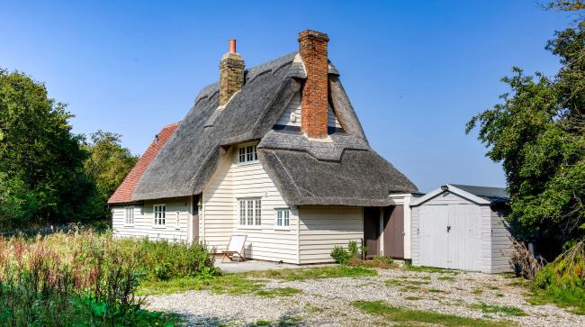 Raindrops-on-Roses Holiday Cottage in Great Hallingbury A slate roofed, clapperboard essex cottage with tall brick chimney stacks.