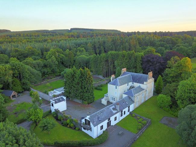 The Old Coach House in Coldingham aerial view of a large country house with attached outbuuildings surrounded by lawns and woodland