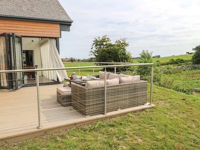 Relax on the deck at Cowslip, a Northumberland Eco-Lodge in Bemburgh. Outdoor seating on a wooden deck of an eco-lodge with bi-fold windows