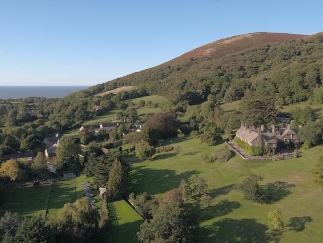 Exmoor Walks Start From the Door Step in Allerford. Image credit: Allerford View An aerial view of a small hamlet nestling beneath a tree and bracken covered moorland hill top.