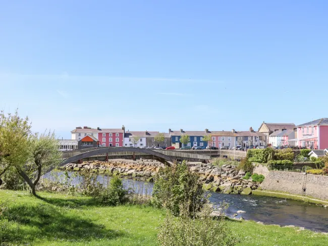 Discover Seaside Holiday Cottages in Aberaeron. A graceful arched bridge spans a river with rocky banks flowing thrioughg Aberaeron