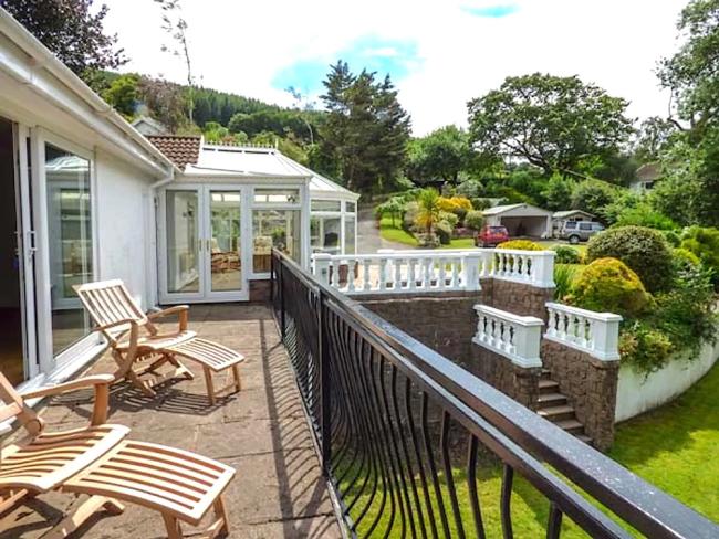 Photocredit: Treetops, Abergavenny. sun loungers on a terrace overlook a large well-maintained garden in Abergavenny.