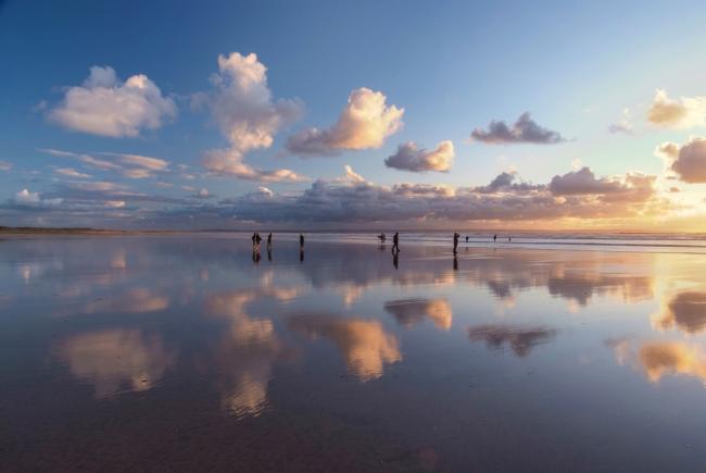 Saunton Sands Holiday Cottages. Small clouds are reflected in the wet surface of a sandy beach in North Devon.
