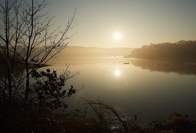 Find South Wingfield Holiday Cottages to Book. Photo credit: Jasmine Cottage A tiny boat is silhoutted in the setting sun on the flat calm surface of a large reservoir.