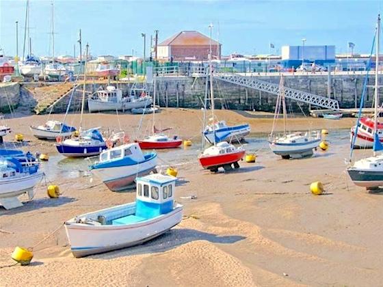 Seaside Holiday Cottages in Rhyll Small boats in a harbour at low tide.