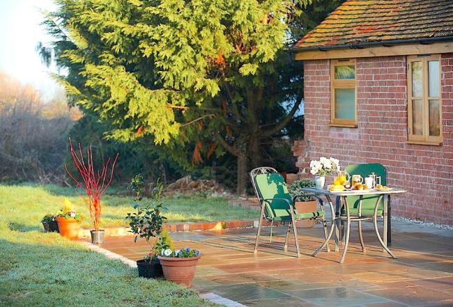 Stay in Preston-Lynne Holiday Cottages A table for two laid for tea on a cottage courtyard.