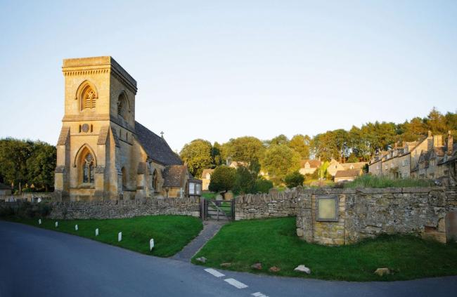 A Cotswold church and a cluster of honeystone cottages.