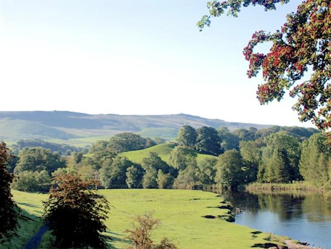 A view of Wharfedale from Skipton on a summer afternoon A still river winds through tree-lined fields.