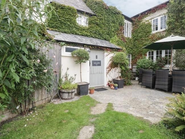 Find Country Cottage Holidays in Winsham. A farmhouse overlooks a garden courtyard.