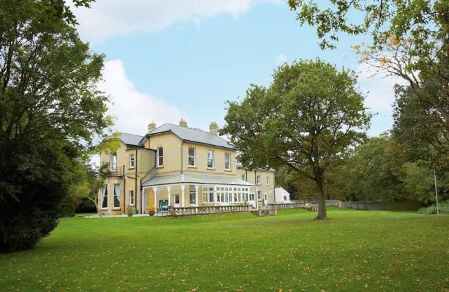 Find UK Holiday Homes Large Enough to Offer Group Accommodation The drive and exterior of a large Isle of Wight holiday cottage surrounded by lawns.