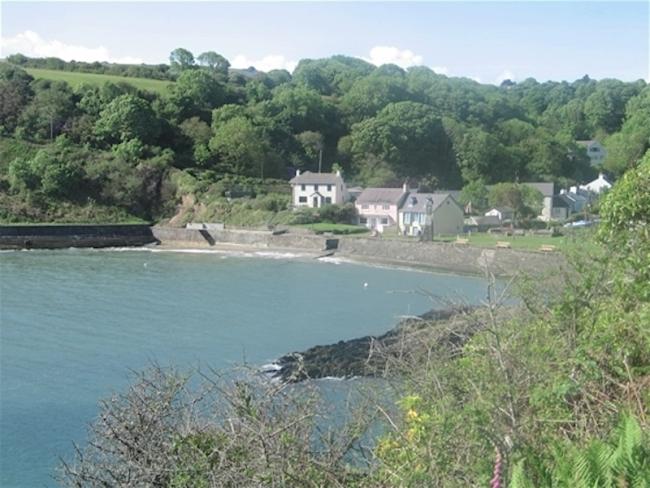 A cluster of houses overlook a small sandy cove with the sea at high tide