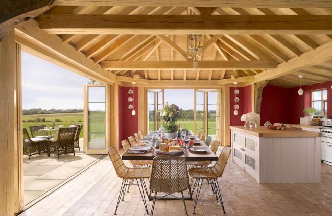 A dining table for 12 is laid for dinner under the oak beams of a country cottage kitchen.