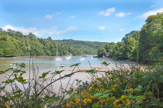 Find Self-Catering Holiday Homes Bookable Through Established Agencies. Small boats moored on a sandy river creek lined by mature woods at low tide,