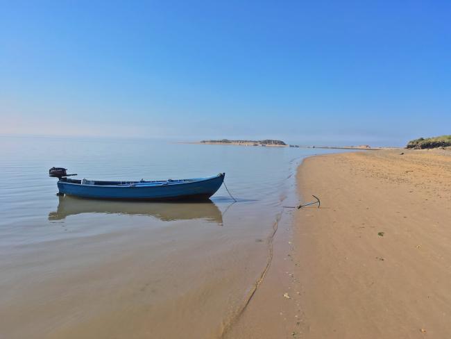 Find and Book North Devon Holiday Cottages A long rowing boat anchored at the tide's edge to a sandy beach in North Devon