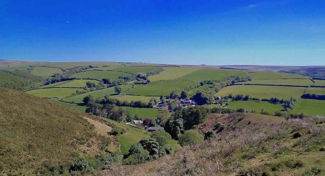 Book Oare Holiday Cottages For Scenic Riverside and Moorland Walks Close to The North Devon Coast Panoramic view of a tiny village nestling in a wide Exmoor valley with fields and woods