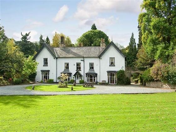 Large rural Shropshire manor house with two end gables overlooks a large, tree-lined lawn.