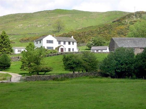 A Cumbria holiday cottage at the foot of a hill surrounded by fields and mature trees