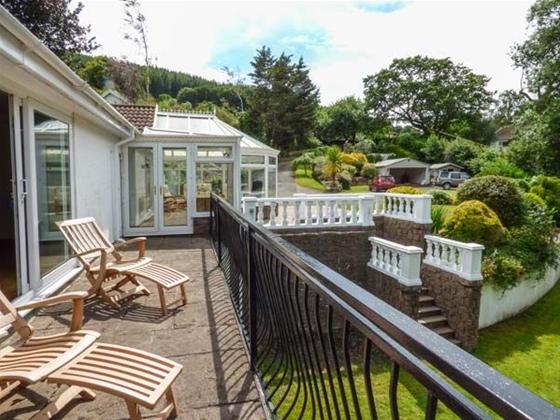 A bungalow with a sun room and terrace overlooks a sunken garden.