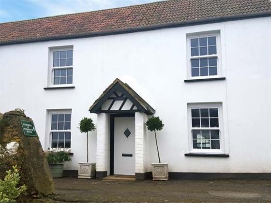 A double-fronted, white rendered Ilfracombe cottage with traditional sash windows