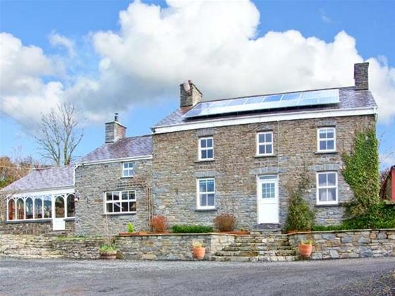 A detached, double fronted, stone-built cottage with a front garden behind a low stone wall.