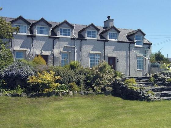 A row of terraced houses look down over a flower-filled rockery to a large lawn.