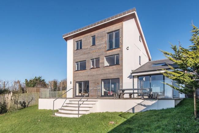 Modern, 3-storey Dorset eco-lodge overlooking a patio and large lawn.