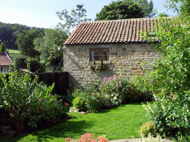 North Yorkshire barn conversion surrounded by a lawn, trees and mature shrubs