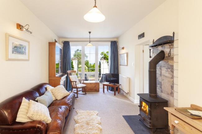 A Exmoor coastal cottage lounge with leather sofas, French windows to a garden.
