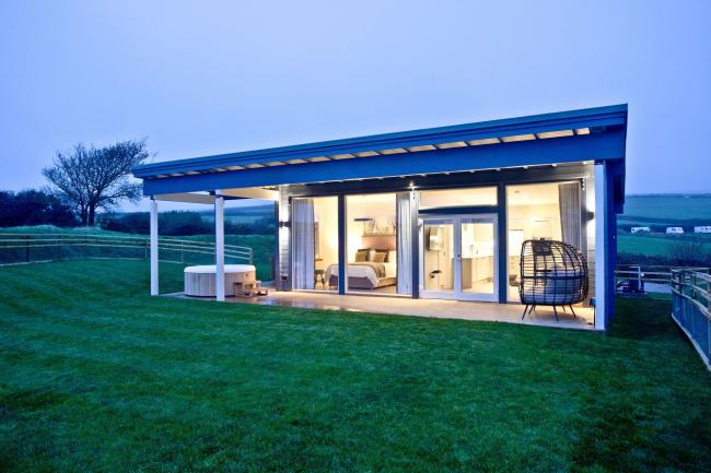 A contemporary glass-fronted eco-lodge with a hot tub and large garden.