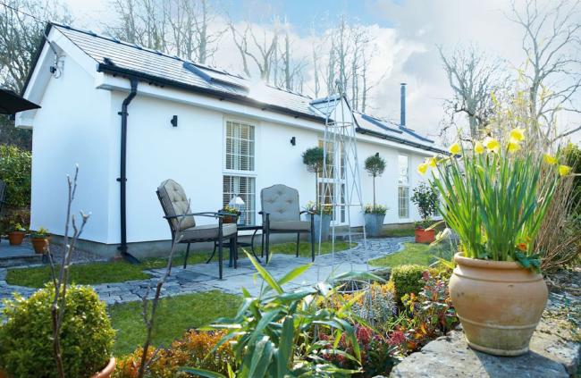 Single storey holiday cottage in Glamorgan with a terrace bordered by a low stone wall.