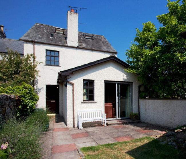 Exterior of a holiday cottage in Cark-in-Cartmell overlooking a small patio and lawn.