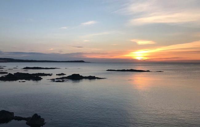 Tiny islands, silhouetted against a setting sun on a calm sea on the Moray Firth in Scotland.