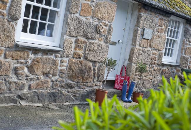 Ground-floor frontage of a stone-built holiday cottage in Mousehole.