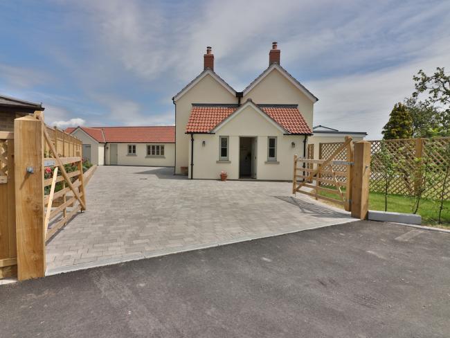 Atwin-gabled contemporary house with a large drive and secure fenced garden.