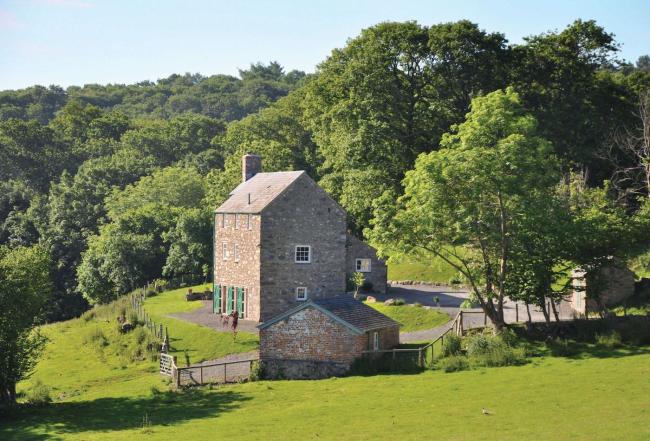 A 3-storey, brick-built Welsh holiday cottage surrounded by lawns, fields and woodland