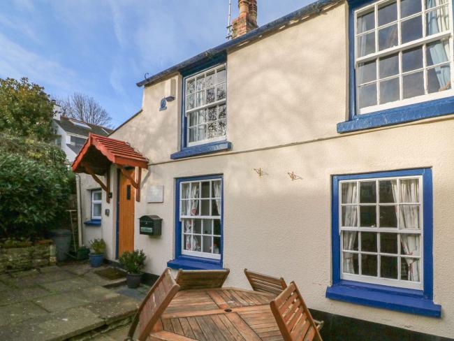 Exterior of asemi-detached restored fisherman's cottage with a paved courtyard in Appledore.