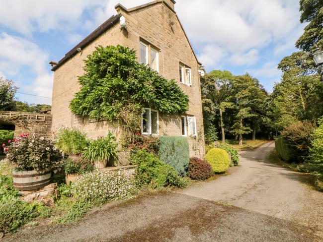 Gable end of a 2-storey pennine holiday cottage overlooking a country lane