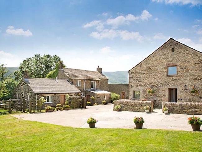 A 2-storey barconversion with a low stone wall overlooks a paved drive and a spacious lawn.