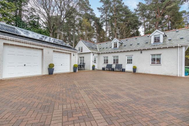 A large inverness-shire holiday cottages and two double garages surround a large block-paved courtyard.