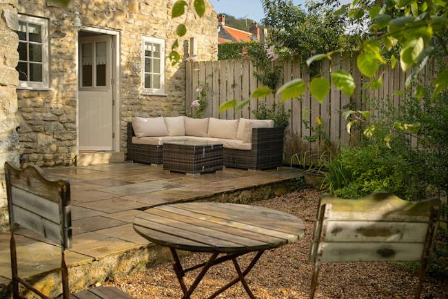 A stone built holiday cottage in Ampleforth with a deck and courtyard containing outdoor seating option.