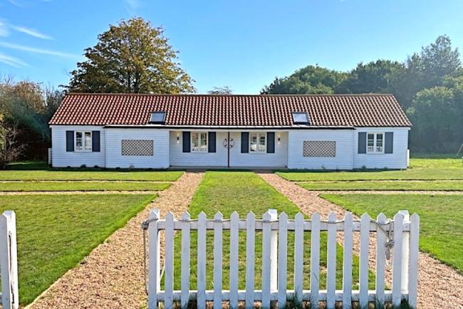 A single-storey holiday cottage on Osea Island overlooks a large lawn.