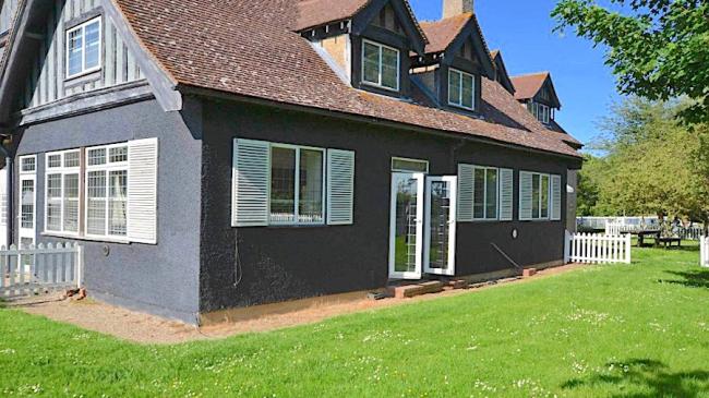 Semi-detached holiday cottages on Osea Island with dormer windows in the roof and French windows, overlooking a large lawn