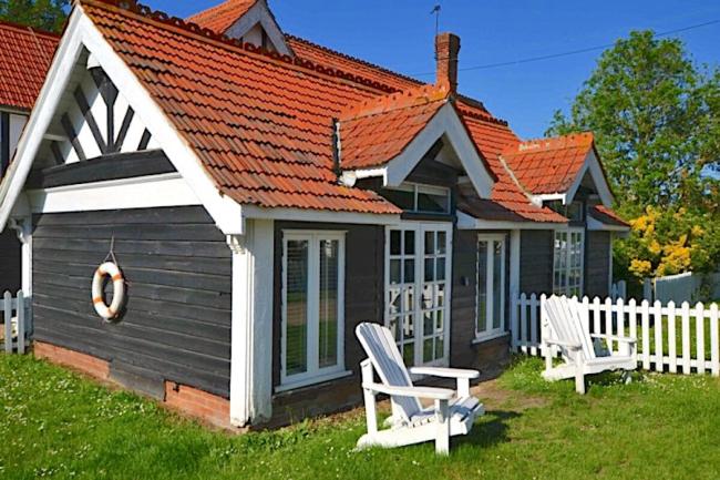 A timber-framed holiday cottage on Osea Island with two sun-loungers on its lawn