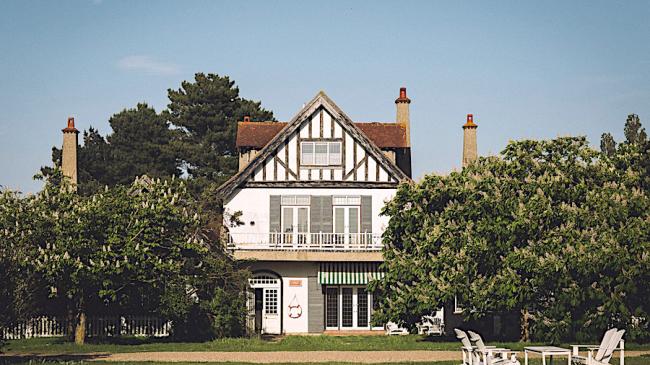 Gable end of an Essex holiday apartment with large balcony and flanked by horse chestnut trees.