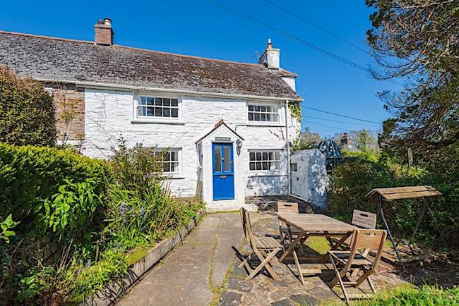 A stone-built Feock holiday cottage overlooks a flagstone patio with outdoor tables and chairs