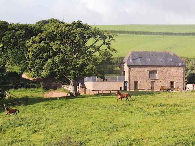 A large large stone barn conversion in Devon surrounded by open fields and mature trees