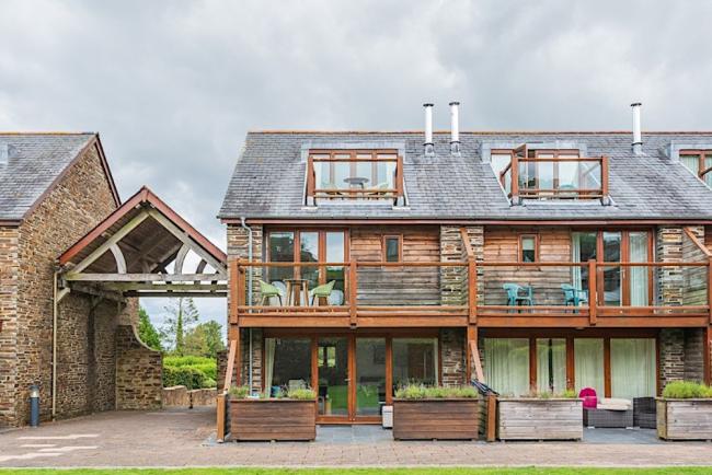 3-storey contemporary holiday home with large balcony and patio overlooks a lawn.