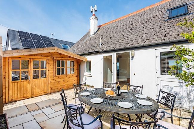 A single-storey holiday cottage overlooks a courtyard with a table laid for a meal